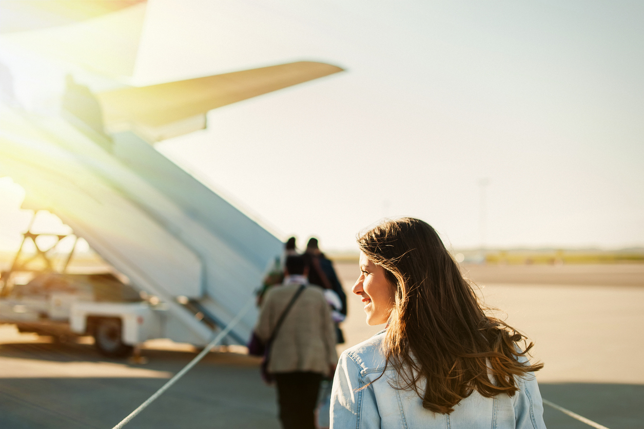 923799162 Woman tourist passenger getting in to airplane at airport, walking from the terminal to the plane.