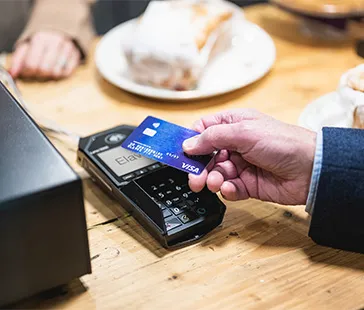 Contactless card payment being made using a card reader on a wooden table