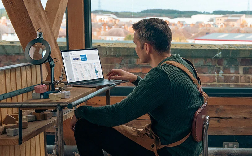 Person reviewing payment transactions and sales data on a laptop in a workshop