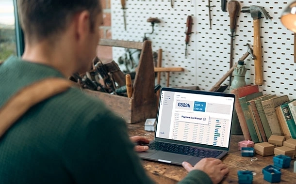 Person reviewing payment transactions and sales data on a laptop in a workshop