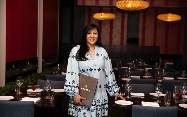 Rupa Dewan standing beside a dining table in a contemporary restaurant interior