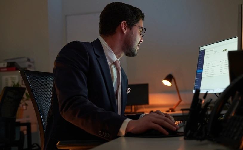 Person seated at a desk working on a computer in a low lit office environment