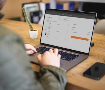 A laptop displaying the Elavon Connect portal on screen, placed on a wooden desk with a blurred background.