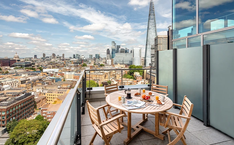 Luxury rooftop apartment balcony in London with breakfast setup and stunning views of The Shard and surrounding cityscape