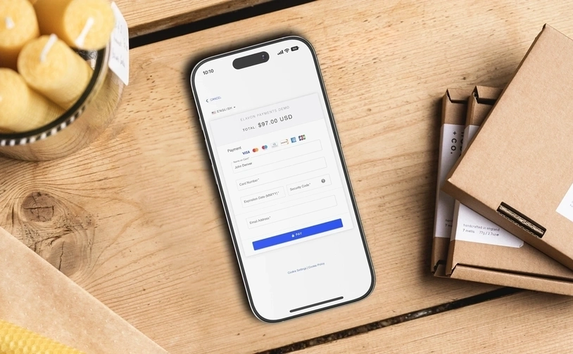Smartphone displaying online payment form for card transaction next to packaged products on a wooden table