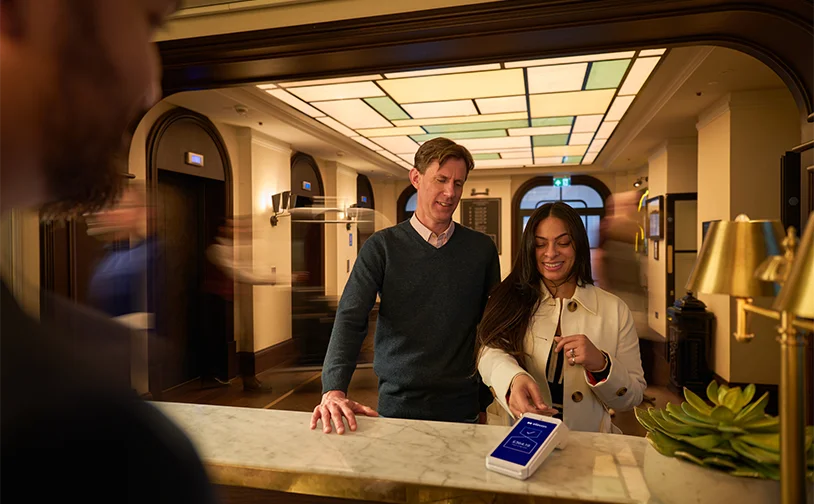 Hotel reception lobby with a couple using taptopay with Amex