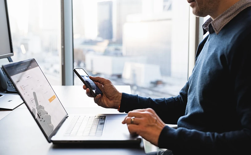 Business user accessing online systems from a laptop and mobile phone