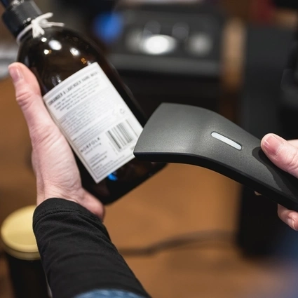 Retail staff scanning a product barcode with a handheld scanner for accurate inventory and point-of-sale processing. 